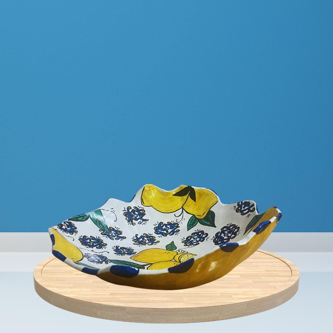 Hand-painted ceramic bowl with white base, wavy edge, and colorful lemon and floral design, including yellow lemons, blue patterns and green leaves.